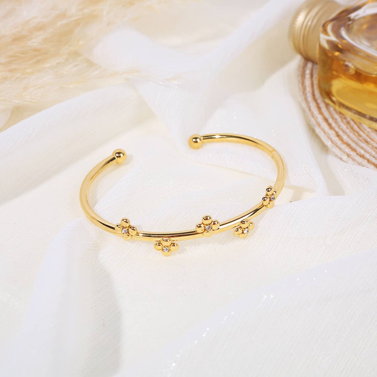 Offener goldener Armreif mit goldenen Perlen und Blumenverzierung