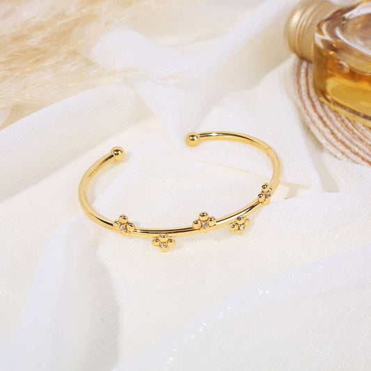 Offener goldener Armreif mit goldenen Perlen und Blumenverzierung