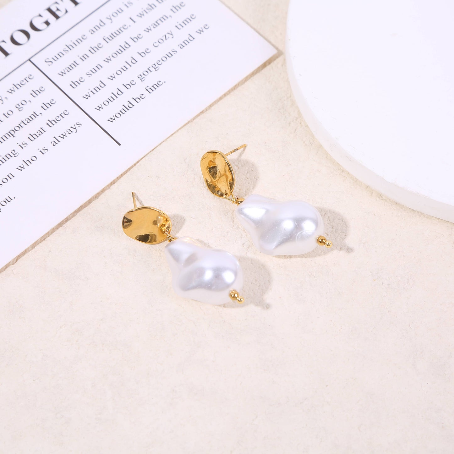 Goldene hängende Ohrringe mit weißer Perle